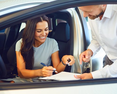 A young woman buys a car in a car showroom